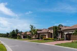 A property manager talks with tenants outside a suburban rental home surrounded by well-kept landscaping.