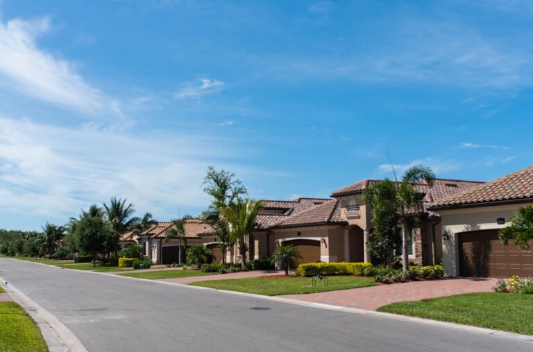 A property manager talks with tenants outside a suburban rental home surrounded by well-kept landscaping.